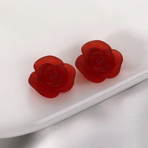 Frosted red rose resin flower charms on a white porcelain tray with satin fabric