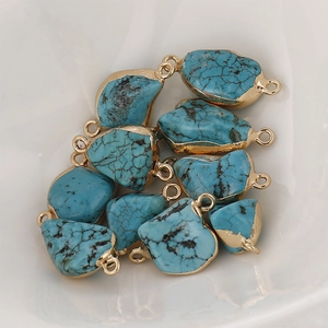 Macro detail of 10 turquoise stones with gold edges and loops on a ceramic plate