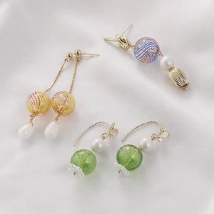 Detailed view of handmade vintage glass bead earrings with pearls and gold accents on silk