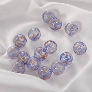 Macro shot of glass beads with blue and brown spirals on white silk fabric for DIY