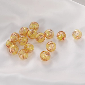 Macro detail of round glass beads with orange spiral patterns for DIY jewelry making