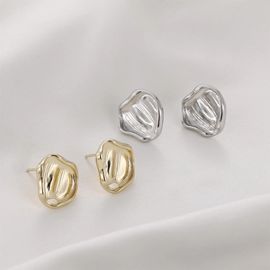 Close-up of irregular crumpled 14K gold plated earrings on white silk fabric background