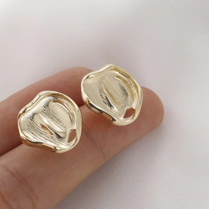 Macro detail of irregular 14K gold-plated earrings with molten lava texture and mirror finish