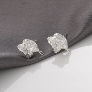 Dettaglio macro di orecchini color argento opaco texture lava con anelli per DIY