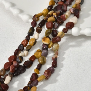 Close-up of irregular earth-toned natural gemstone beads on a white ceramic plate