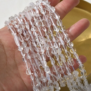 Macro shot of transparent 5-8mm irregular natural crystal beads on a golden tray