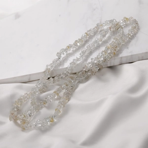 Macro view of irregular natural crystal beads on white marble and silk background