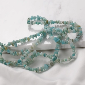 Detailed view of 3-5mm irregular amazonite crystal stone beads on white silk fabric