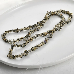 Close-up of irregular 3-5mm Dalmatian Jasper beads in a spiral layout on white tray
