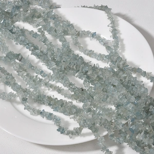 Macro view of 3-5mm irregular light blue crystal gemstone beads on a white plate