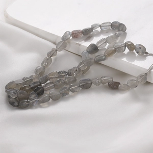 Macro detail of irregular labradorite stone beads showing natural blue flashes on white silk