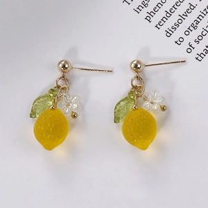 Macro detail of handmade lemon earrings with yellow resin fruit and green leaf charms