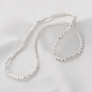 Polished silver pumpkin-shaped beads for DIY jewelry making displayed on soft white fabric