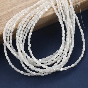 Nahaufnahme von weißen ovalen Muschelperlen mit Perlmuttglanz für DIY Schmuckherstellung