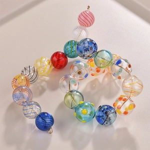 Macro shot of colorful striped glass beads with floral patterns on a curved gold wire