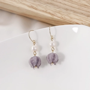 Detailed shot of purple lily bell glass flower earrings with elegant white pearl accents