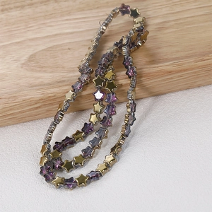 Macro detail of 8mm purple star beads with metallic golden finish for jewelry making