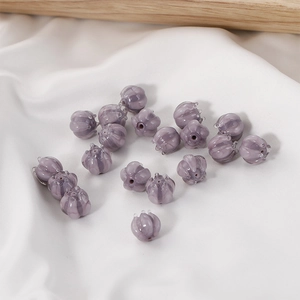 Macro shot of purple lily of the valley glass beads on white silk for DIY jewelry