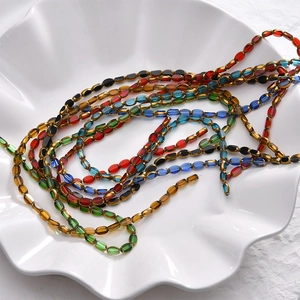 Colorful faceted oval glass beads for DIY jewelry making on white decorative tray