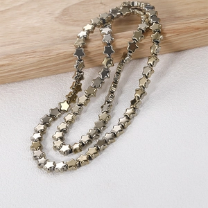 Close-up of 8mm metallic star-shaped beads for jewelry making on a wooden display