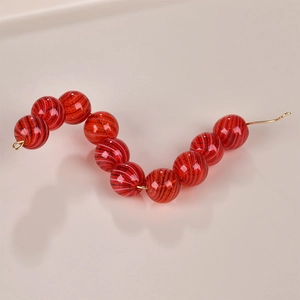 Macro shot of 10 red striped glass beads with inner spiral texture on gold wire
