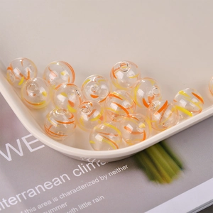 Macro detail of clear glass beads with orange and yellow spiral patterns for DIY jewelry