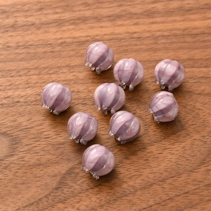 Detailed view of nine violet lily-of-the-valley glass beads on a textured wooden surface