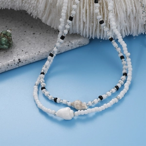 Detail of seashell beach necklace featuring black and white beads with natural conch pendants