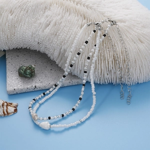 Double-layered beaded necklace with black and white beads featuring natural seashell charms