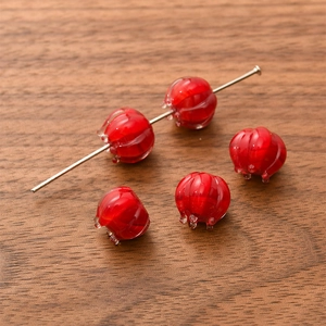 Macro shot of red glass bell orchid beads with vertical textures on a wooden surface
