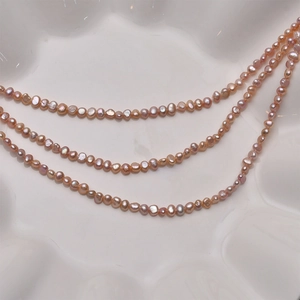 Fili di perle d'acqua dolce barocche rosa champagne 3-4mm su un piatto in ceramica