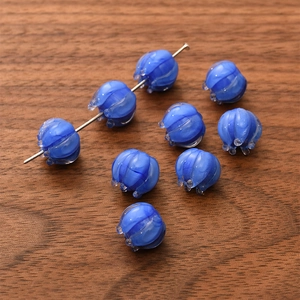 Macro detail of blue glass lily of the valley beads with white texture on dark wood background