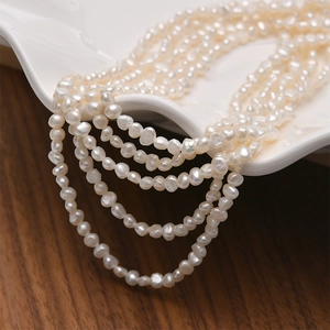 Collana multifilo di perle d'acqua dolce barocche naturali su un piatto di ceramica bianco