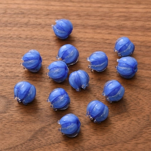 Detailed view of thirteen blue glass lily of the valley beads on a wooden texture background