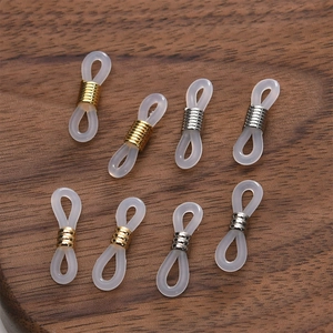 Macro detail of 18k gold and silver eyeglass chain silicone connectors on wood