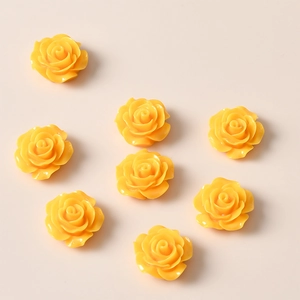 Macro view of eight bright yellow resin rose flower charms for DIY jewelry making