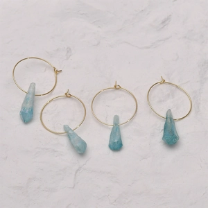 Detailed close-up of light blue irregular crystal pendants on gold hoop earrings