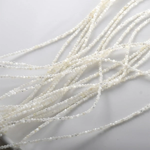 Makroaufnahme von 4 mm facettierten weißen Perlmuttperlen mit irisierendem Glanz für DIY-Schmuck