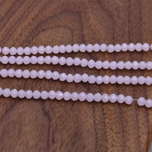 Detail of 4mm faceted pink crystal glass beads for DIY jewelry making on dark wood