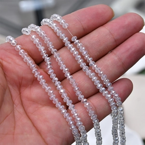 Close-up of hand holding multiple strands of 4mm faceted AB clear crystal glass beads