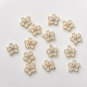 Macro view of cherry blossom pendants with pink resin petals and gold metal frame
