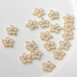 Detailed view of cherry blossom pendants with pink petals and gold plated metal settings