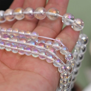 Close-up of iridescent crystal beads showing aurora rainbow luster in human palm