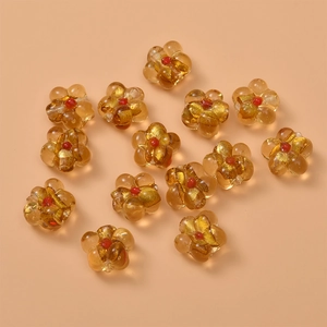 Detailed view of amber glass flower beads with red centers and gold foil for DIY jewelry