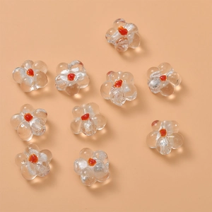 Macro detail of handmade clear glass flower beads with orange center for DIY jewelry making