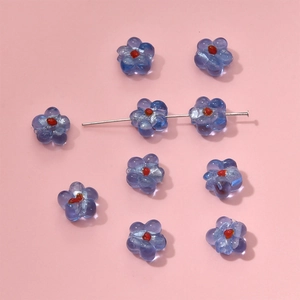 Detailed macro of blue glass flower beads with red centers for DIY jewelry making