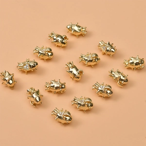 Detailed view of 14K gold plated beetle charms with sparkling white zircon inlays