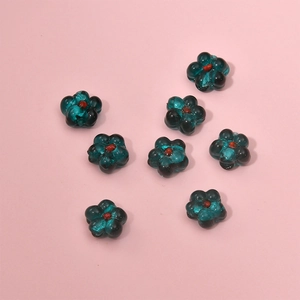 Close-up of translucent dark green glass flower beads for DIY jewelry making and crafts