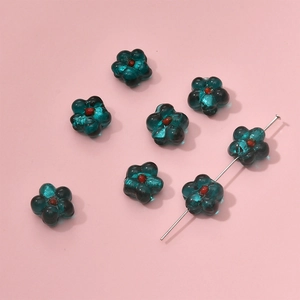 Macro shot of teal glass flower beads with red centers for DIY jewelry making