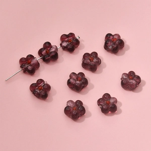Macro detail of dark purple glass flower beads with red centers for DIY jewelry making